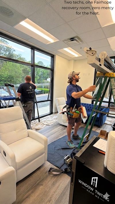 Two technicians installing window tinting in a recovery room.