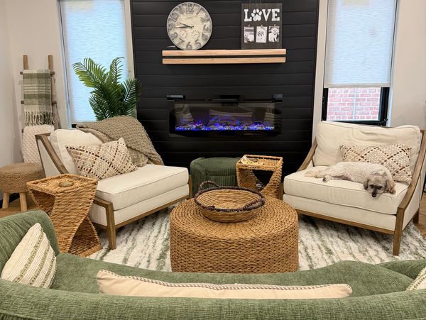 Cozy living room with wicker furniture, a green sofa, and a small dog resting on a chair.