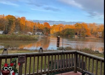 View of a lake and autumn trees from a wooden deck with bird feeders.