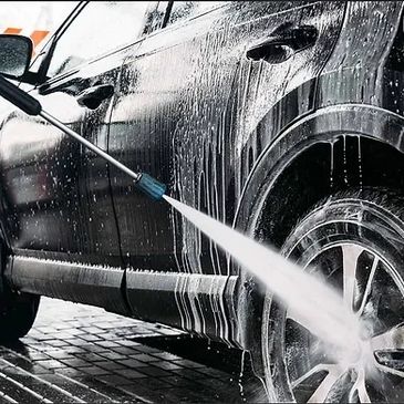 A detailer cleaning the wheels and rims of an SUV.