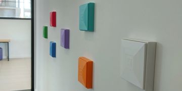 Colorful wall-mounted devices arranged in a pattern inside a bright room.