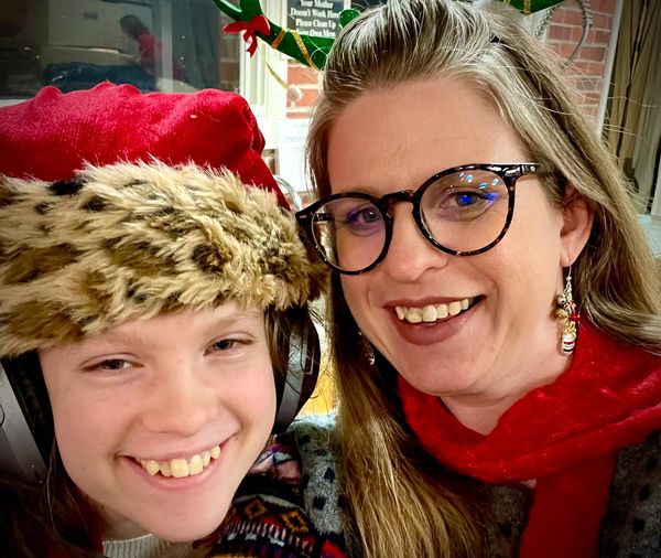 A smiling woman and child in festive holiday attire.