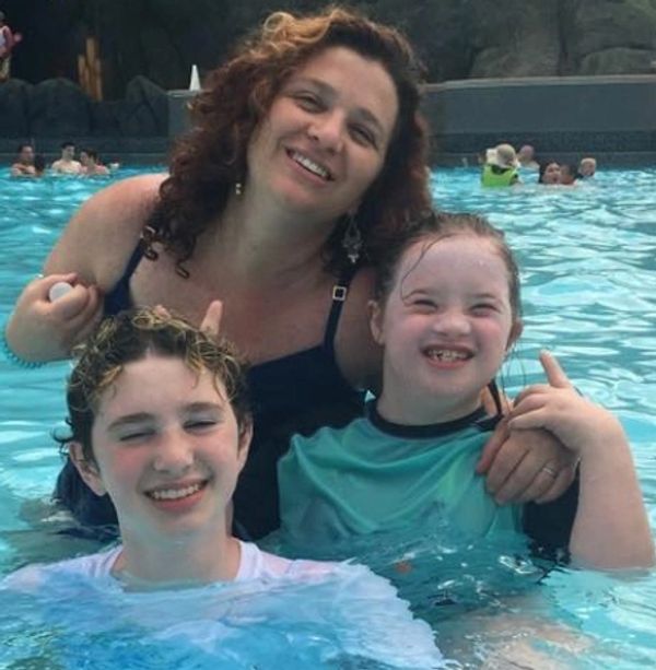 A smiling woman and two children enjoying a swim in a pool.