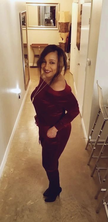 Woman in a red outfit smiling in a narrow hallway.