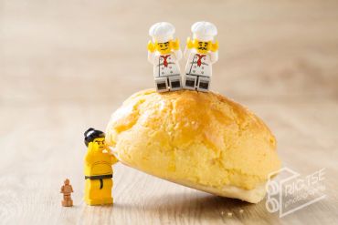 Lego chefs on a bun with a yellow Lego figure and tiny dog below.