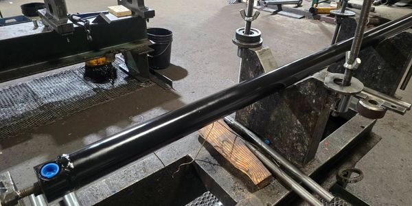 A black hydraulic cylinder mounted on a workbench in a workshop.