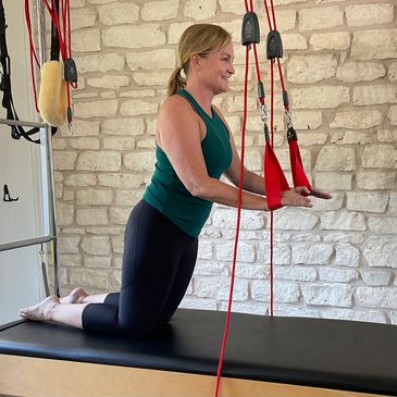 Woman performing kneeling Forward Lean on Redcord apparatus. Austin, Texas