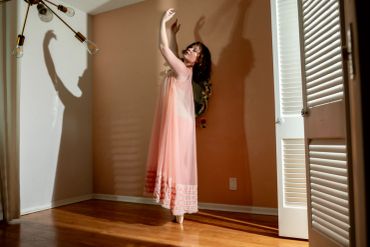Woman dancing in a peach dress casting a shadow.