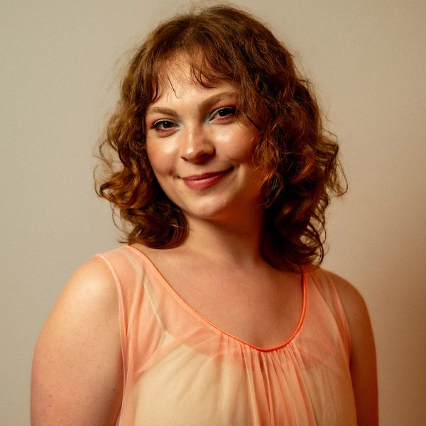 Young woman with curly hair smiling gently.
