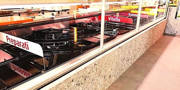 Empty food trays labeled 'Preparati' and 'Vitello' in a cafeteria display case.