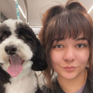 Young woman and her happy black-and-white dog posing for a selfie.