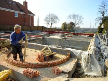 Worker building a curved brick wall at a construction site.