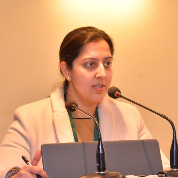 A woman speaking at a podium during a conference or seminar.