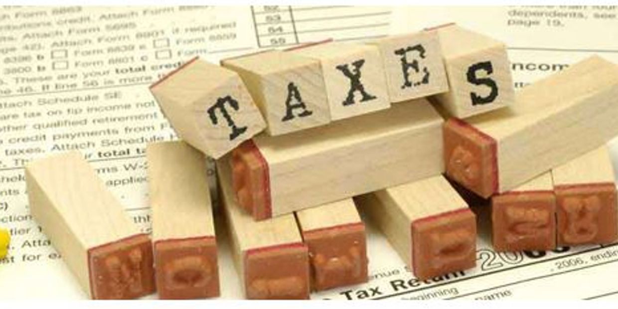 Wooden letter stamps spelling TAXES on tax documents.