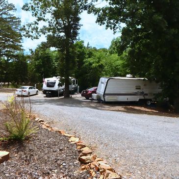 RV and trailer parked among trees in a quiet campground.