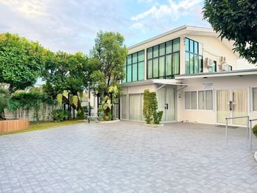 Modern two-story house with large windows and a spacious paved driveway.