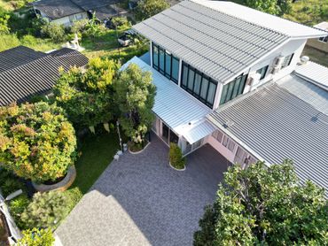 Modern two-story house with a driveway and lush green garden.