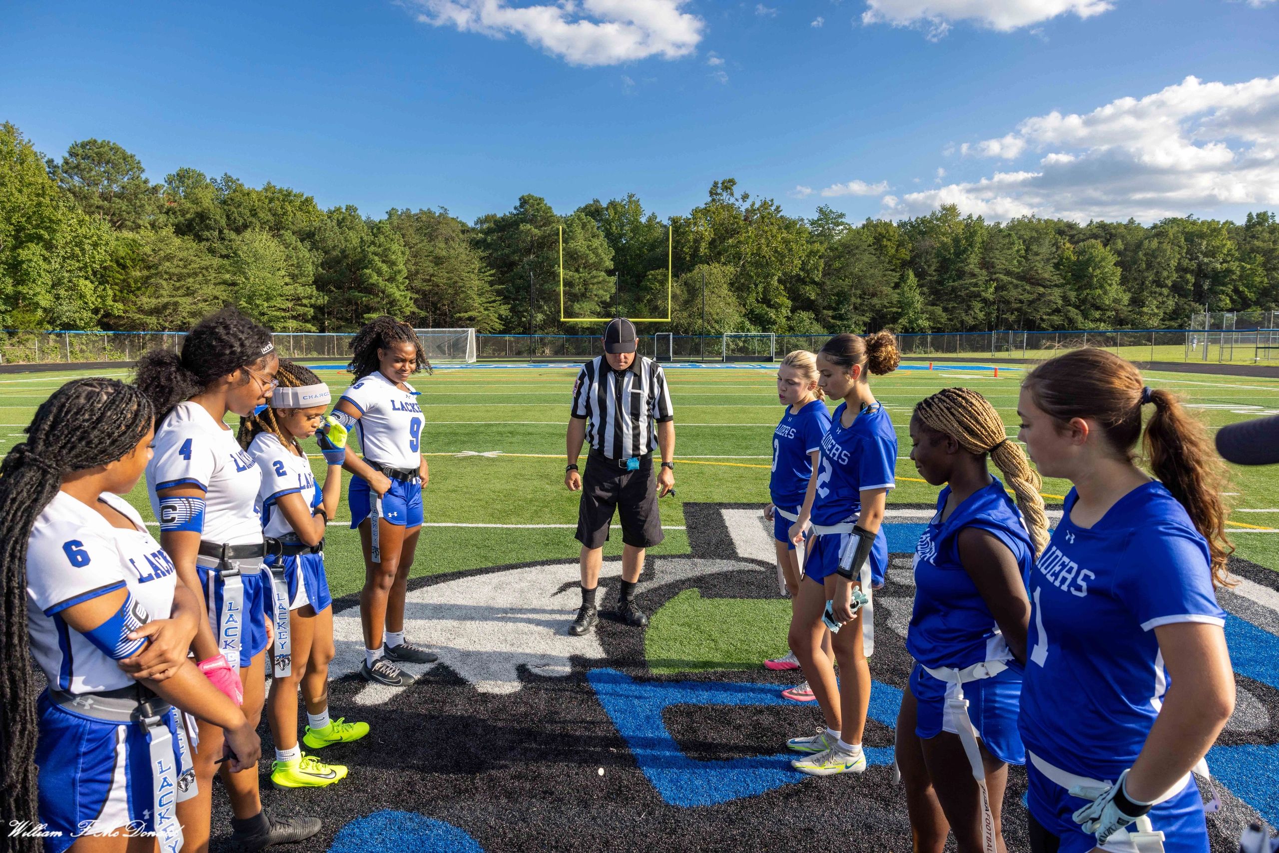 Flag football teams and referee in a pre-game huddle.