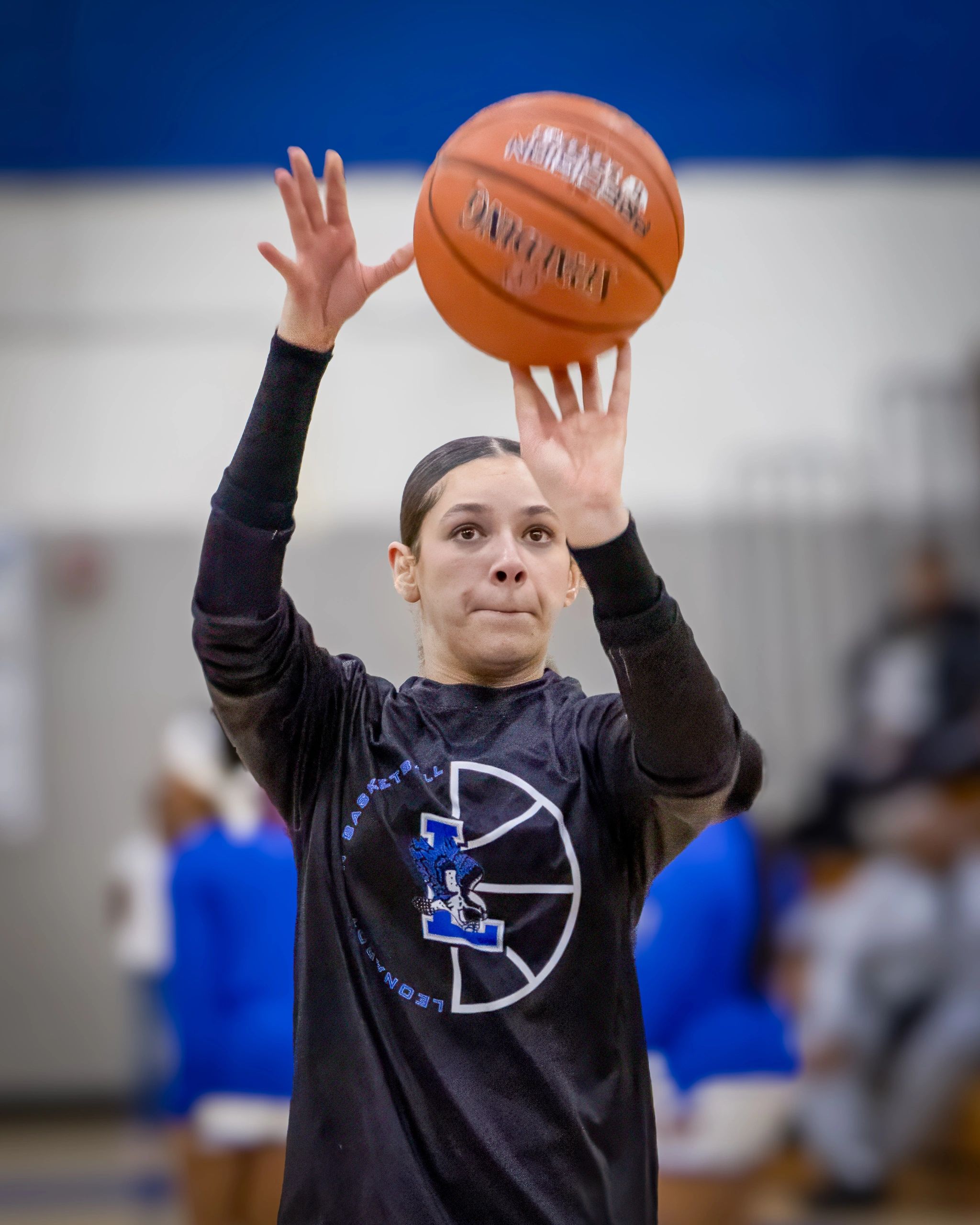 Focused basketball player shooting a ball in a gym.