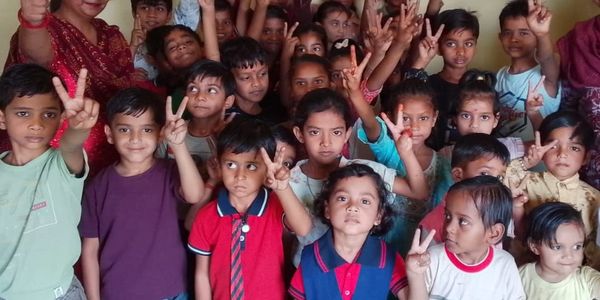 A group of children smiling and making peace signs together.