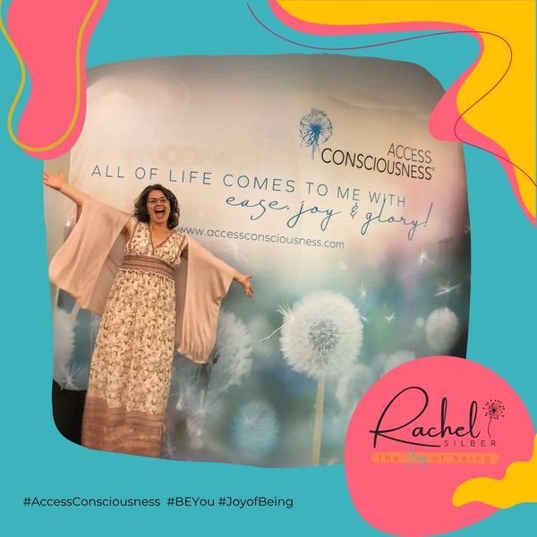 Woman joyfully posing in front of an Access Consciousness backdrop with dandelion imagery.