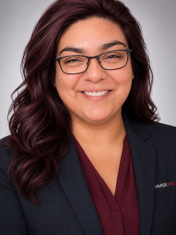 Smiling woman with glasses and dark hair in professional attire.