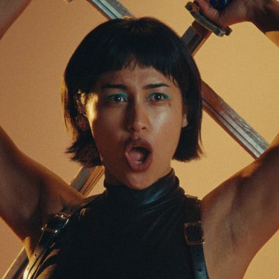 Woman holding a sword behind her head, looking fierce.
