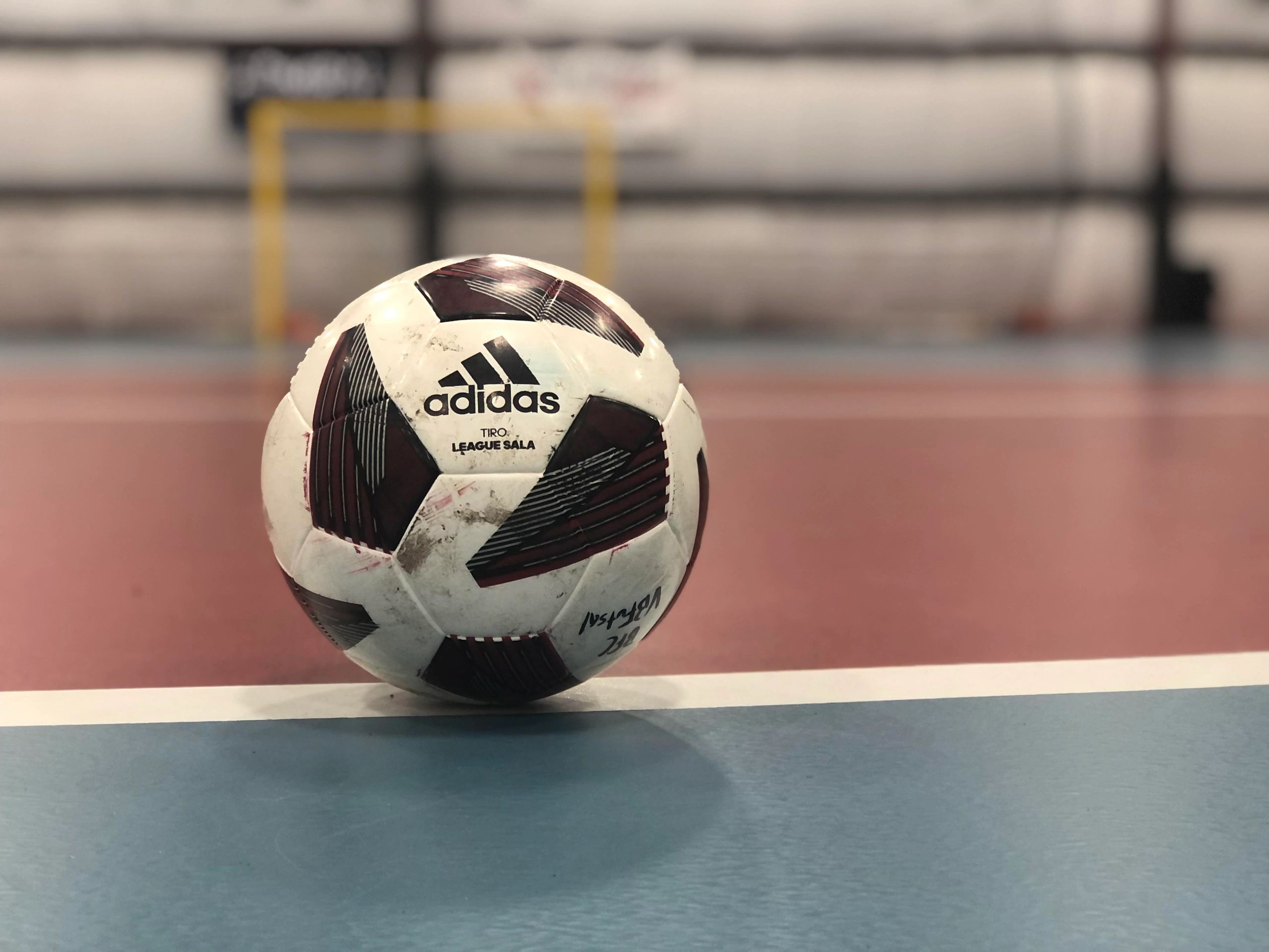 Close-up of an Adidas futsal ball on an indoor court.