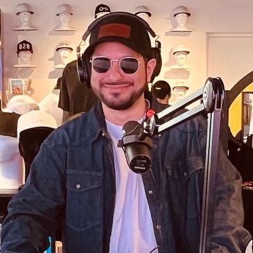 Photo of justPEREZplay in front of a microphone recording a podcast.