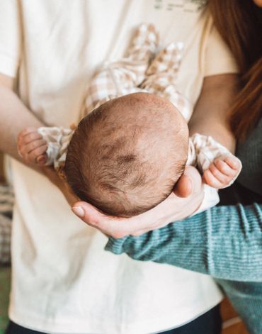 Adult holding a newborn baby gently in their hands.