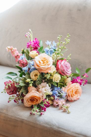 Colorful bouquet of mixed flowers on a couch.