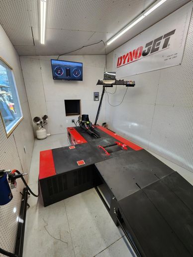 A Dynojet dynamometer in a testing room with monitoring screen.