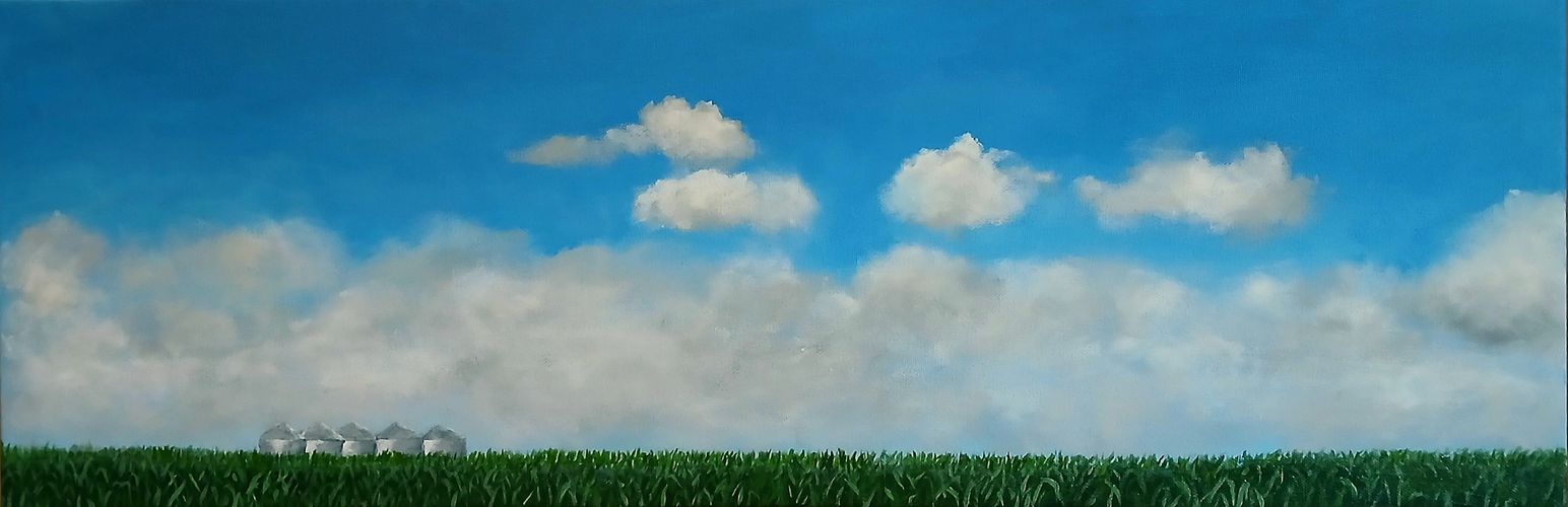 A rural landscape of silos against a brilliant blue sky with clouds.