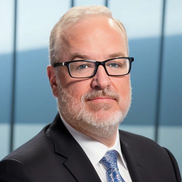 Professional man with glasses in suit and tie, posing confidently.