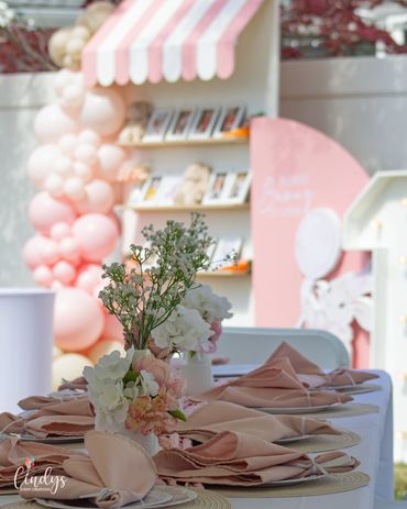 Elegant table setting with pastel pink napkins and floral centerpiece at a festive event.