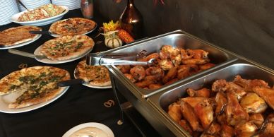 Buffet table with pizza and chicken wings.