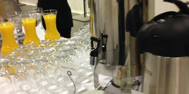 Rows of glasses filled with orange juice and empty glasses.