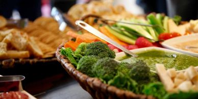 A basket of fresh vegetables and dip at a buffet.