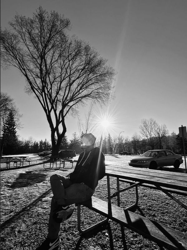 Person sitting on a picnic table on a sunny day with trees and cars in the background - Wardrobe stylist, Edmonton