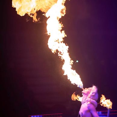 Performer breathing a dramatic plume of fire into the night sky.