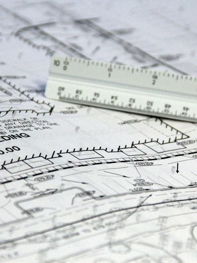 Architectural blueprints with a scale ruler placed on top.