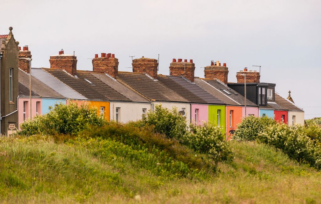 Landscape colour image showing a row of brightly painted houses. 