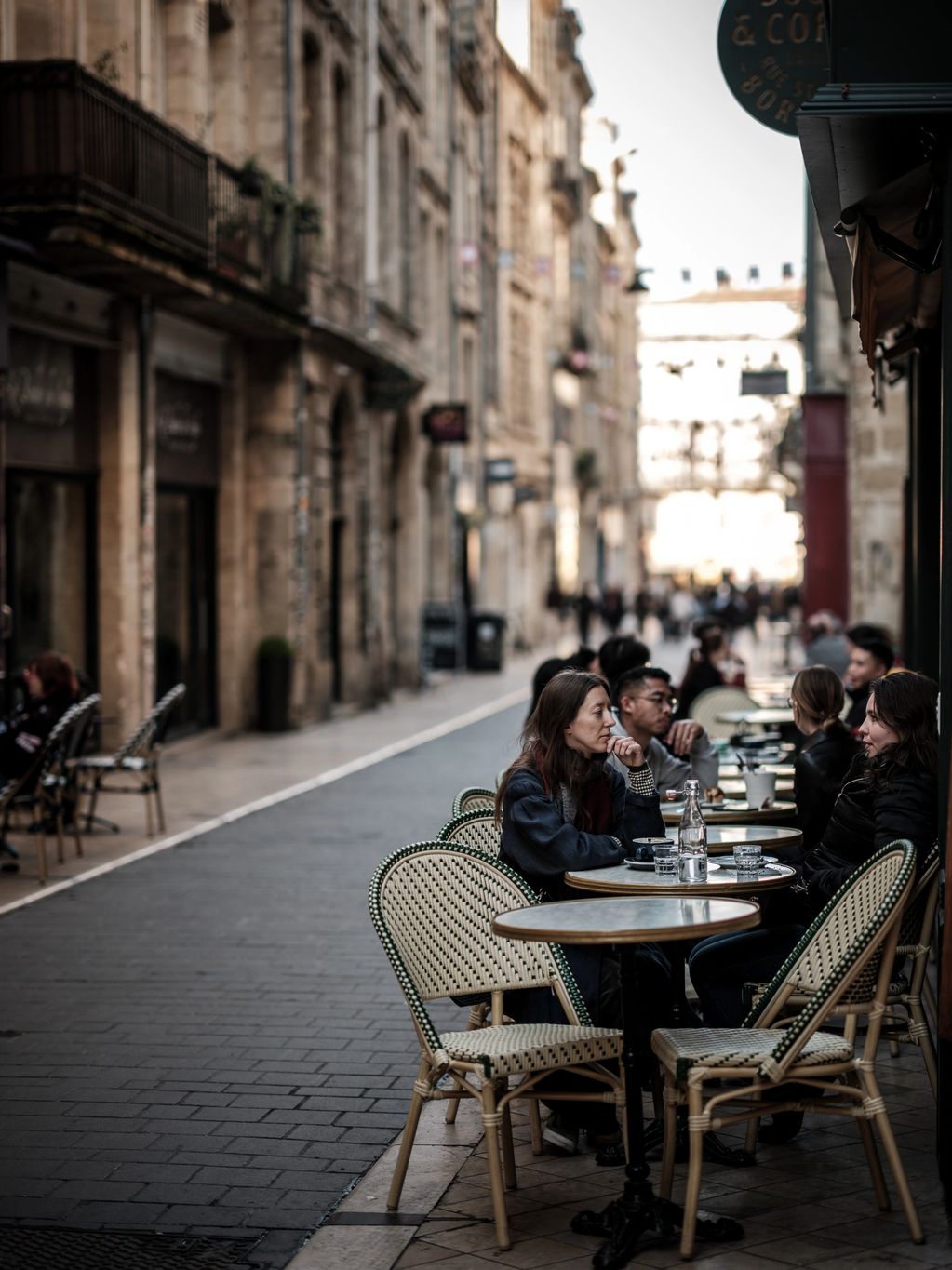 Colour portrait photo of two women sitting a cafe in Bordeaux, France. 