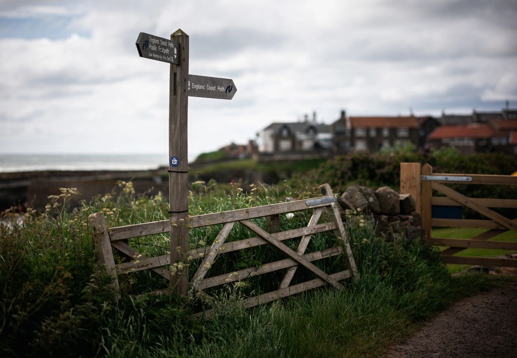 Colour landscape photo showing a signpost directing people to England Coast Path in Northumberland