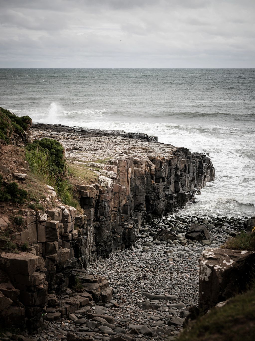 A vertical colour picture depicting the North Sea and a rock pathway, possibly an old launch. 