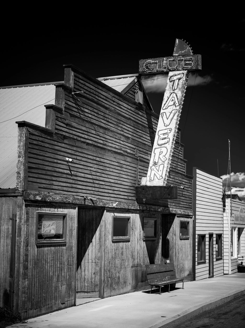 Vertical black and white image showing facade of old bar in Montana, USA. 