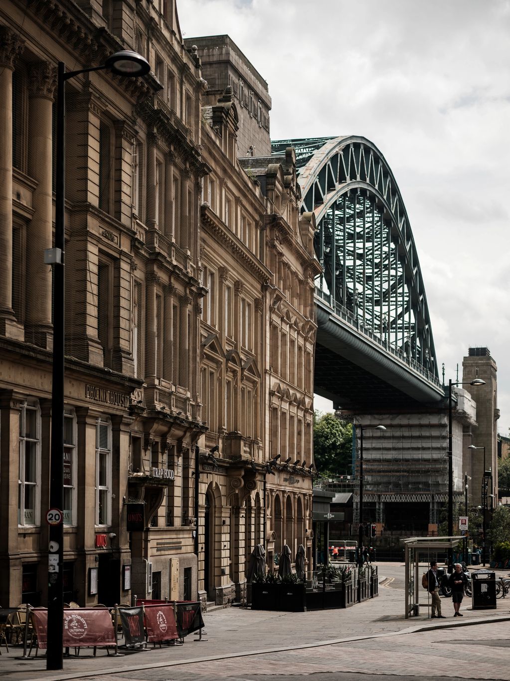 Colour vertical picture showing Tyne Bridge, office and retail storefronts in Newcastle, UK. 