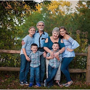 Happy multi-generational family posing outdoors near a wooden fence.