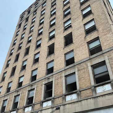 Tall beige brick building with many windows.