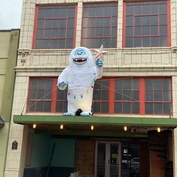 Giant friendly yeti statue with a star and holiday lights.